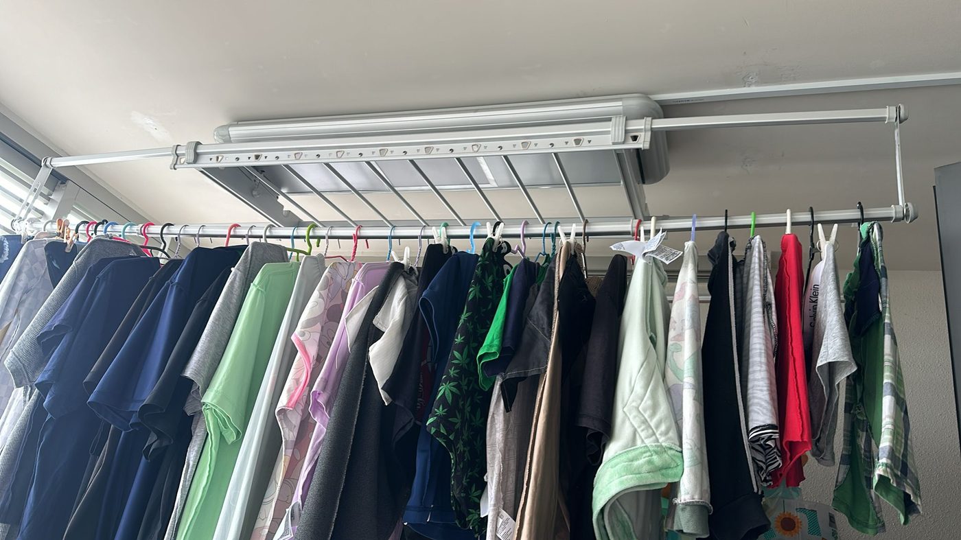 Automated laundry rack holding a full load of clothes spread across the drying rods in a Singapore home