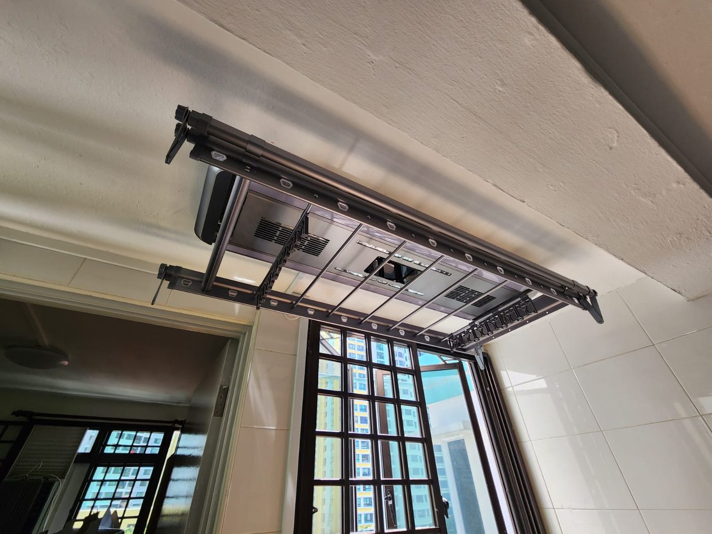 Automated laundry rack installed on the ceiling of an HDB service yard in Singapore, bronze finish, mounted beside a bay window