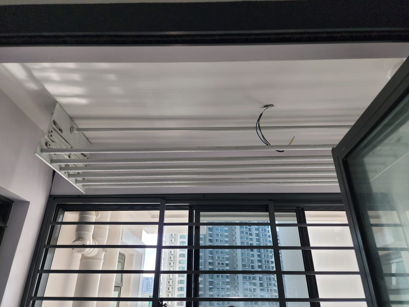 White automated laundry rack installed on the ceiling of an HDB service yard in Singapore